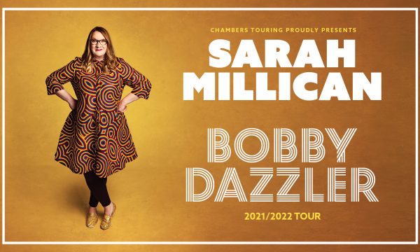 Sarah millican stood in front of a yellow background