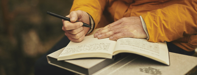 A person sits writing in an open notebook