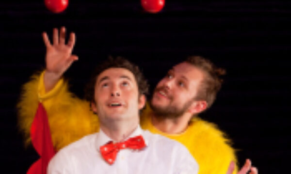 Two men juggling one with a bow tie, one in a chicken costume