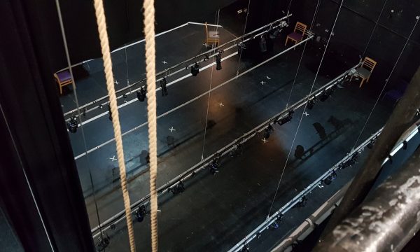 lightings bars suspended on ropes above a black stage