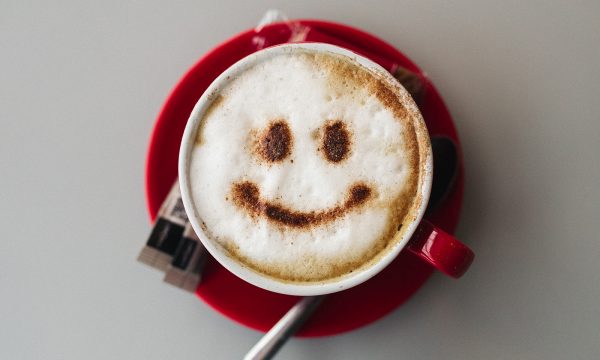 A frothy coffee with a smiley face made in chocolate powder