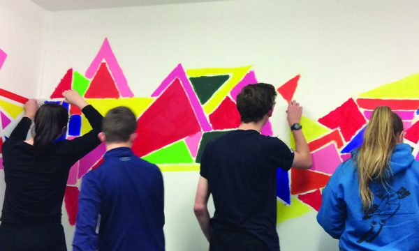 Four people painting on a wall
