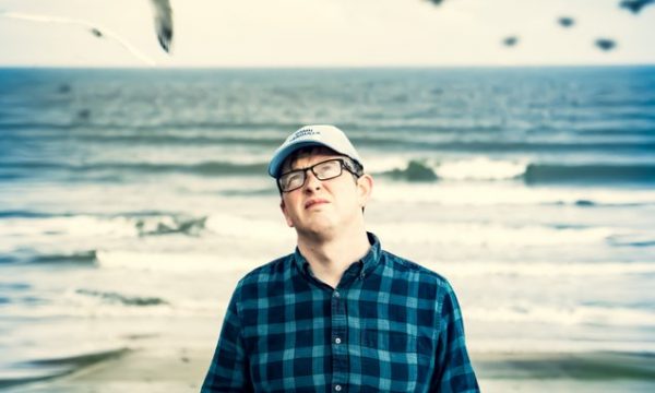 Mike Edwards standing a beach surrounded by seagulls