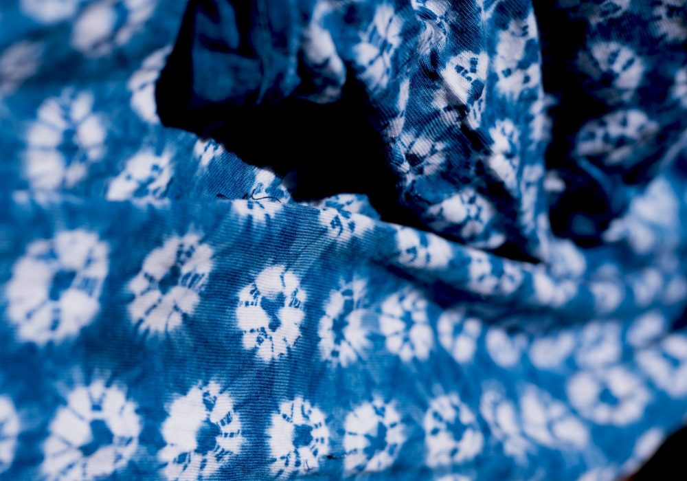 A piece of tie dyed cloth, it is dark blue with white circles
