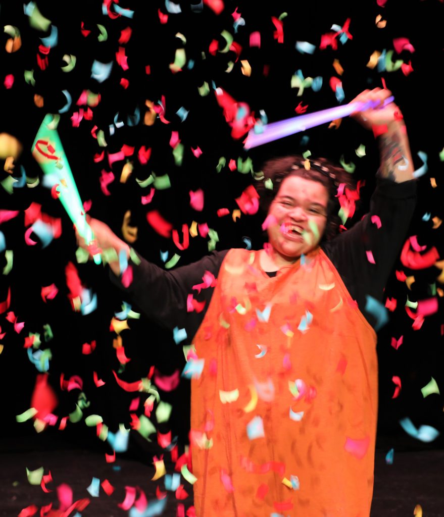 A person waving streamers with confetti falling around them