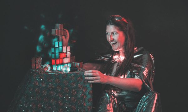 A woman sits by a small table looking in delight at some small coloured cubes