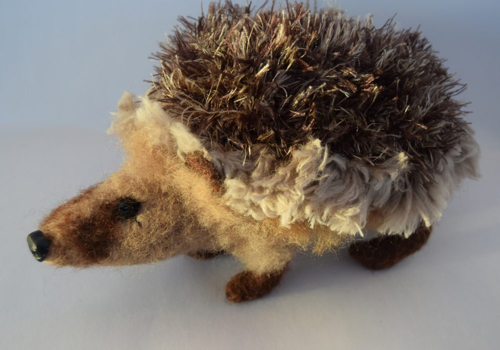 A close up of a felt hedgehog.