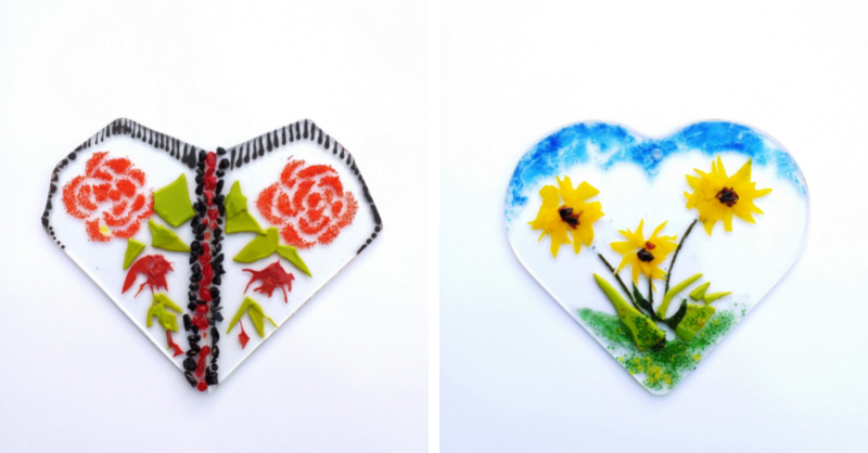 Two clear glass heart ornaments with flower decorations inside