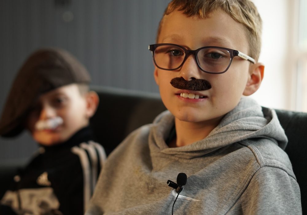 Two primary school age boys wearing fake moustaches