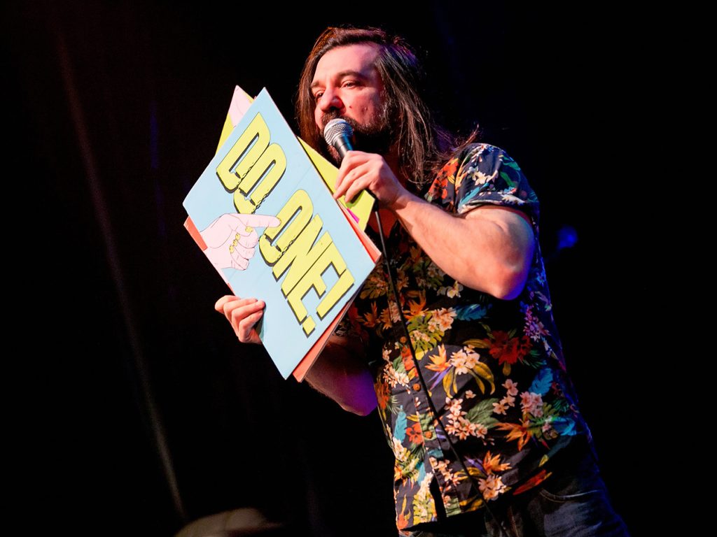 Matt Reed holding a gong sign that says "do one"