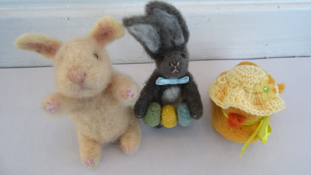 Two needle felted Easter bunnies, and a yellow felted Easter chick.