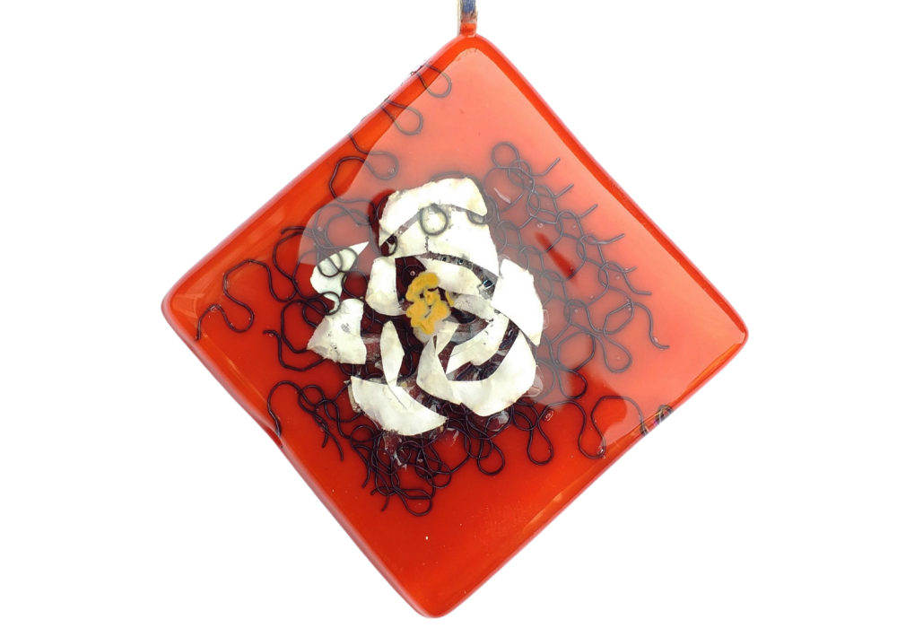 A red glass pendant, with a white glass flower in it's centre.
