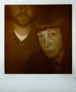 A dark, grainy, Polaroid style photograph of Adam York Gregory and Gillian Jane Lees (you can't see the top half of Adam's head).