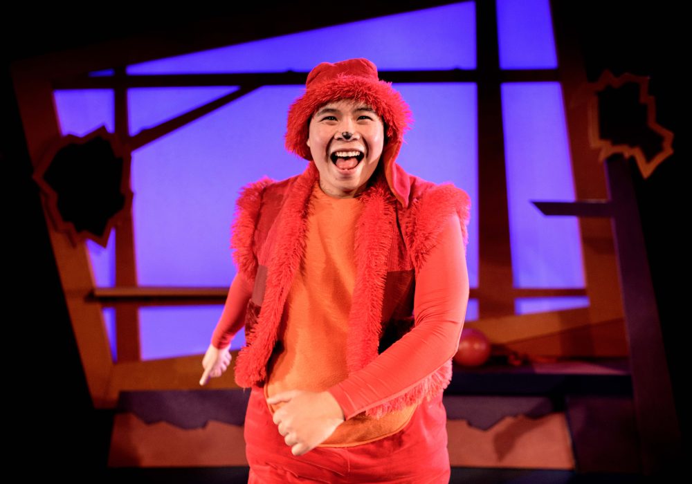 A performer dressed all in orange as George the dog from Oh No, George!