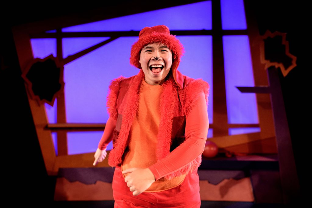 A performer dressed all in orange as George the dog from Oh No, George!