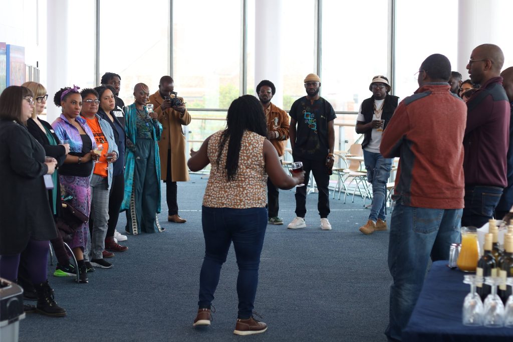 A group of attendees at a Harambee Pasadia event stand in a circle in ARC's second floor gallery space.