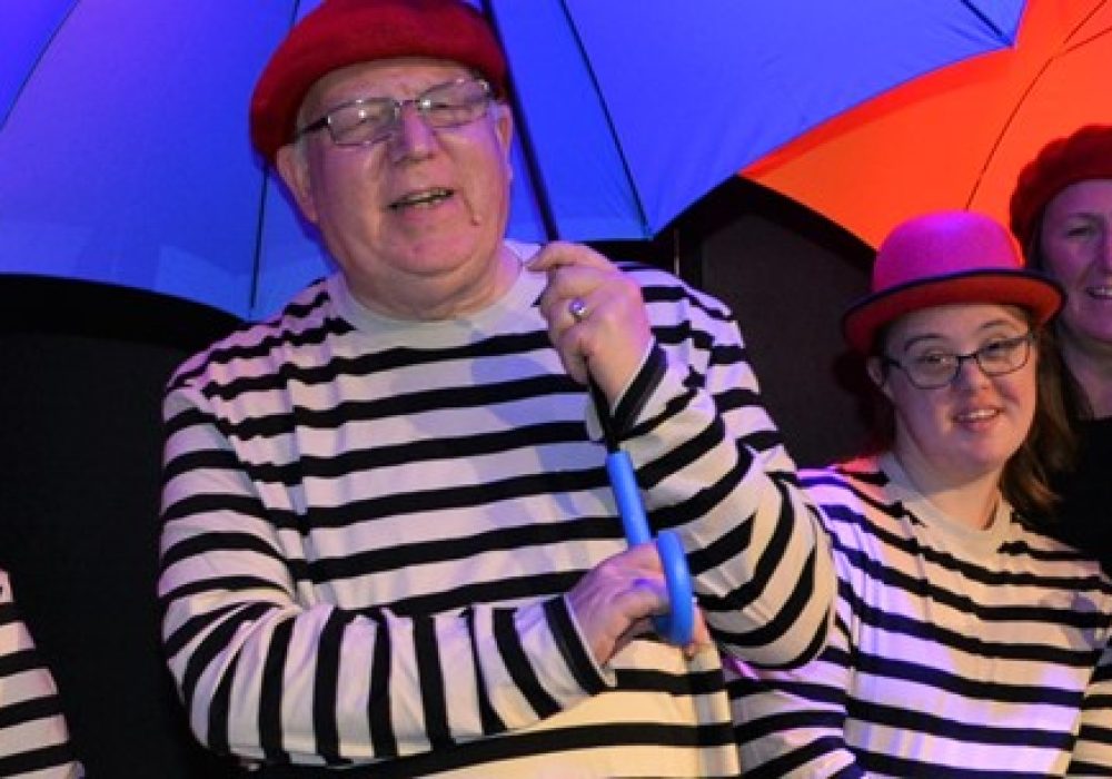 Full Circle actors in matching striped tops holding different coloured umbrellas