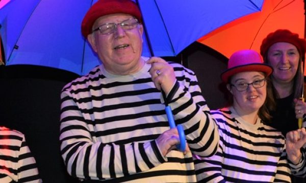 Full Circle actors in matching striped tops holding different coloured umbrellas