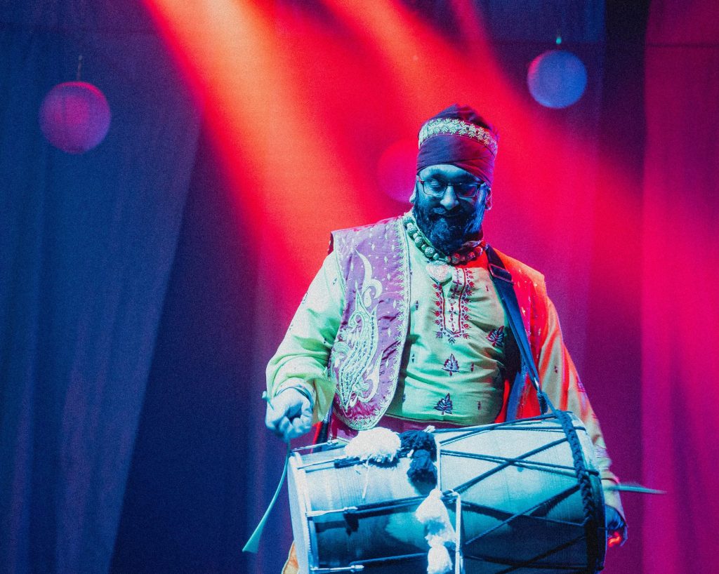Dhol drummer under colourful lights