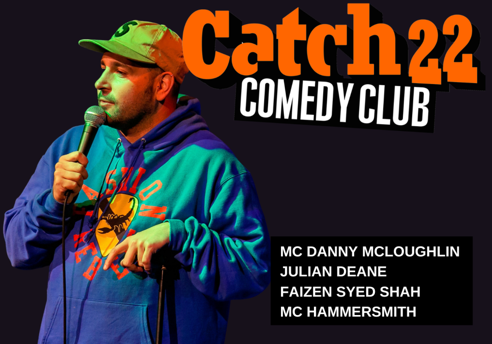 Comedian Danny McLoughlin stands to the left of an orange Catch 22 logo.