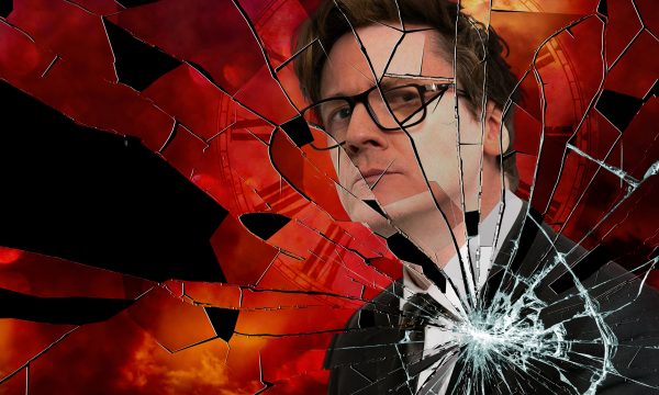 Comedian Ed Byrne looks intensely at the camera, in front of him looks like shattered glass.