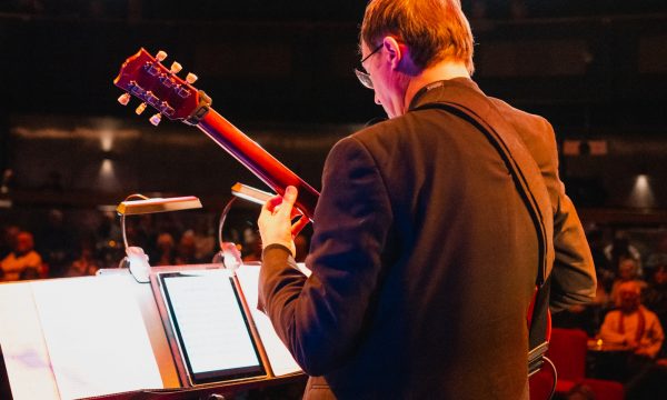 Paul from Pocket Jazz Orchestra playing guitar on stage