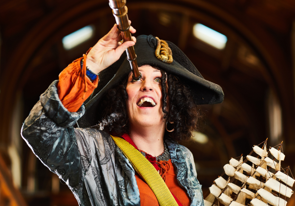 A performer dressed as Pirate Bonnie, wearing a tricorn hat and holding a telescope to her eye.