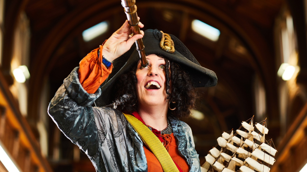 A performer dressed as Pirate Bonnie, wearing a tricorn hat and holding a telescope to her eye.