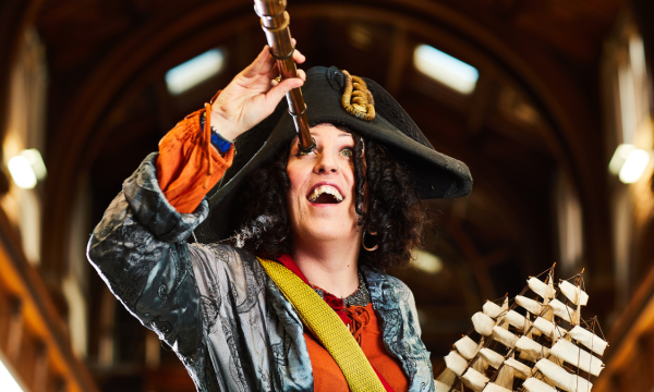 A performer dressed as Pirate Bonnie, wearing a tricorn hat and holding a telescope to her eye.