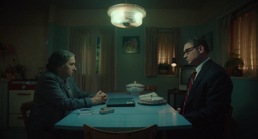 Helen Mirren portrayed as Golda Meir sat at a table smoking with Henry Kissinger