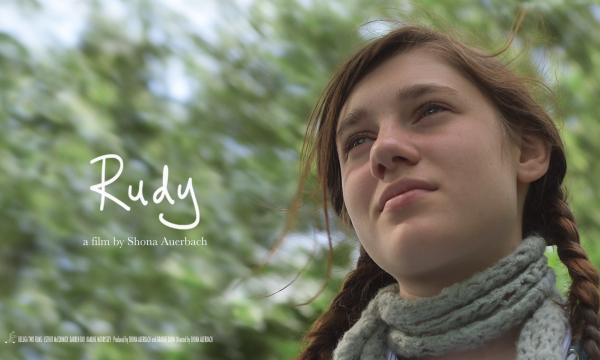 A girl with brown hair in a grey scarf reading Rudy a film by Shona Auerbach