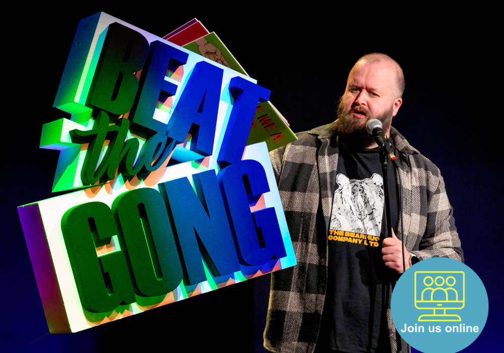 Comedian Freddy Quinne standing to the right of an illuminated Beat the Gong logo.