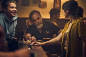 A girl behind a bar serving two men