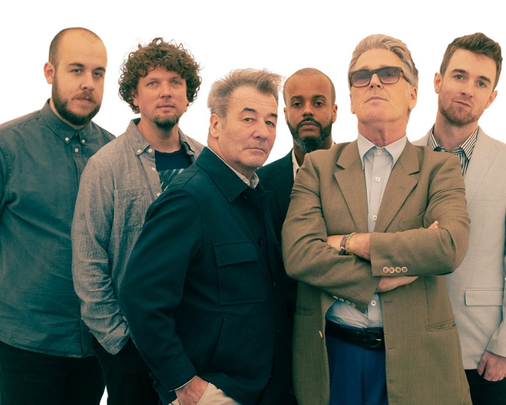 6 members of China Crisis stand together facing you