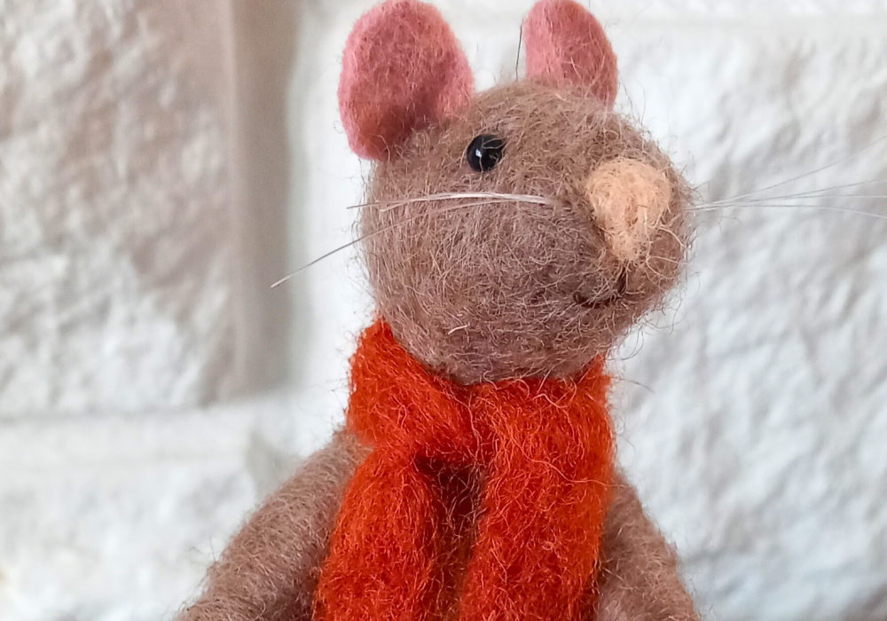 A brown, needle felt mouse wearing a red felt scarf.