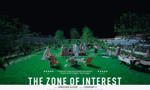 The Zone of Interest advertising poster showing people on a green lawn with tents and picnic chairs, to the left the barbed wire of Auschwitz