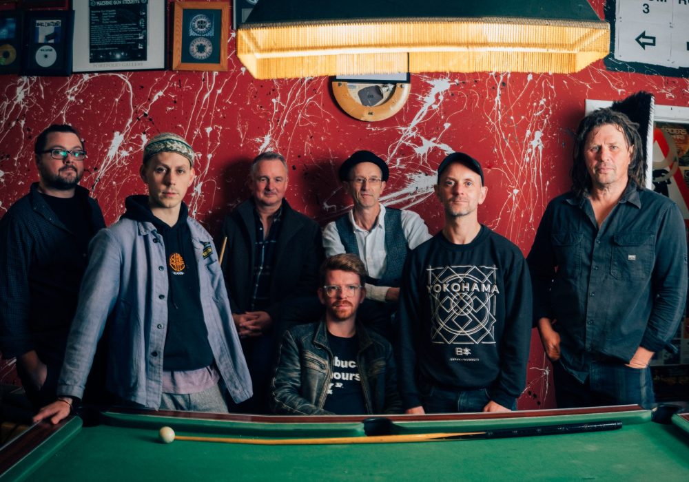 7 people from Peatbog Faeries stand against a snooker table