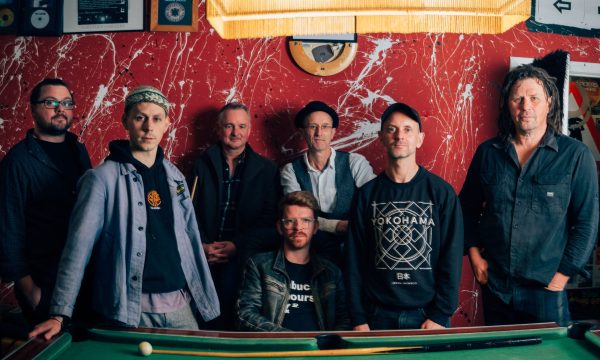 7 people from Peatbog Faeries stand against a snooker table