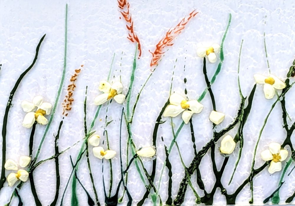 A row of delicate flowers painted on a sheet of white glass.
