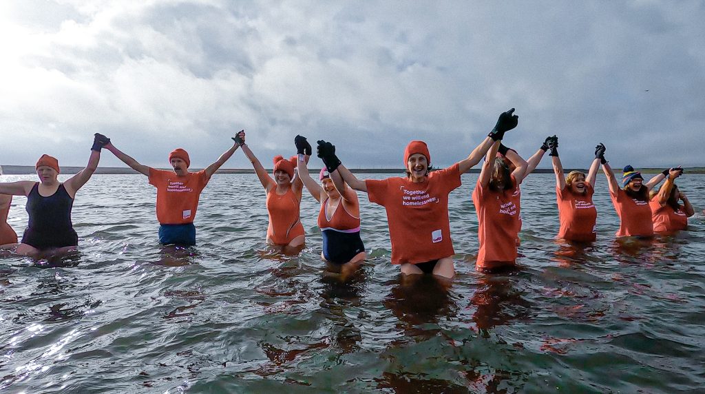 A group of individuals gleefully standing in ice cold water