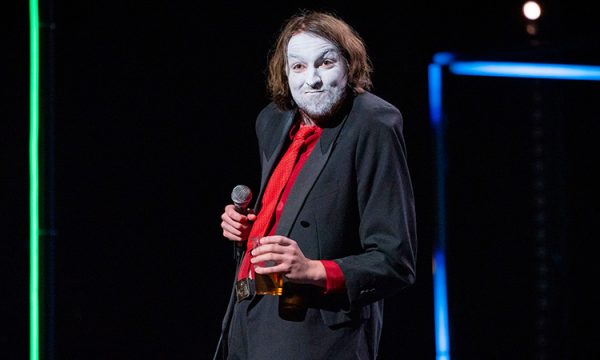 An image of Joe Kent-Walters on stage, wearing thick white stage make-up on their face.