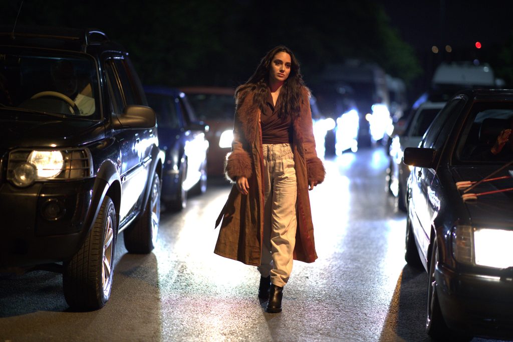 Main character, Leila walking through traffic deep in thought.