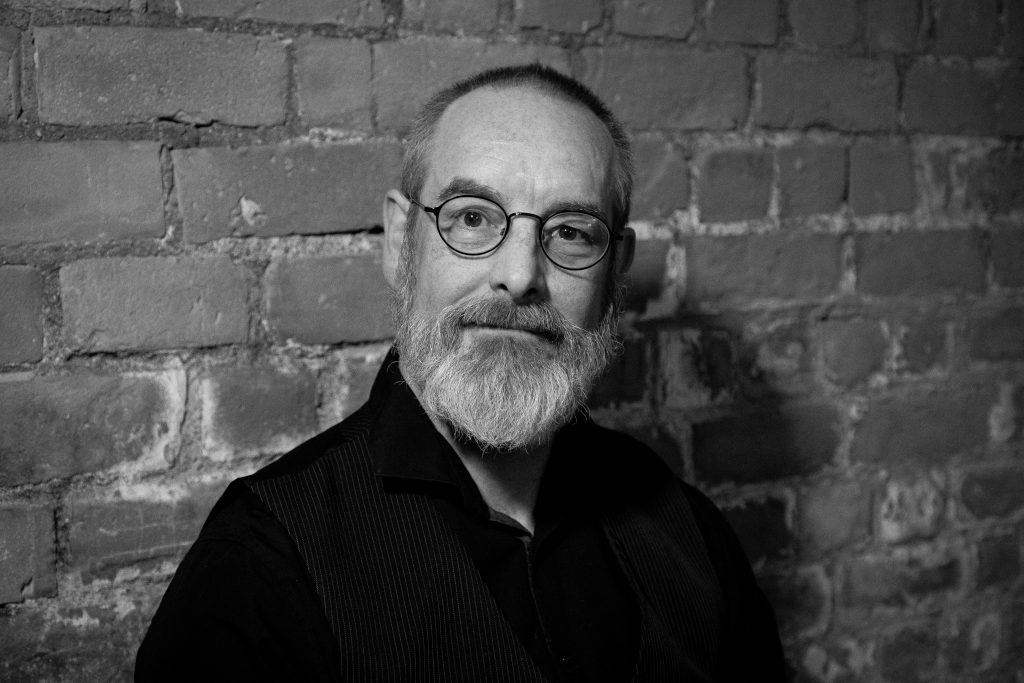 A black and white headshot of Dr Bob Beagrie, a white man, with shortly cropped hair and a grey beard.